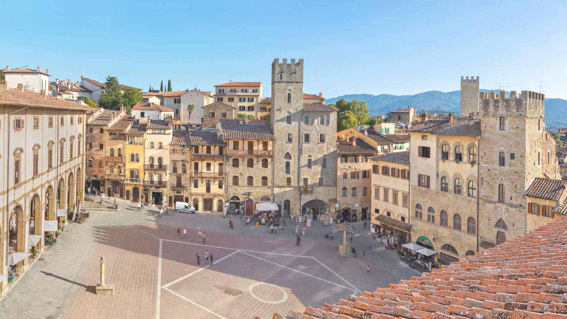Medieval square with historic buildings and a stone tower.