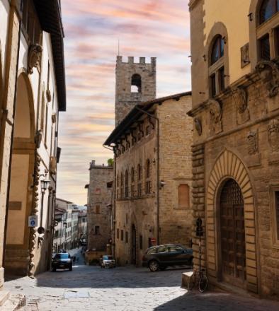 Medieval street with historic buildings and sunset sky.