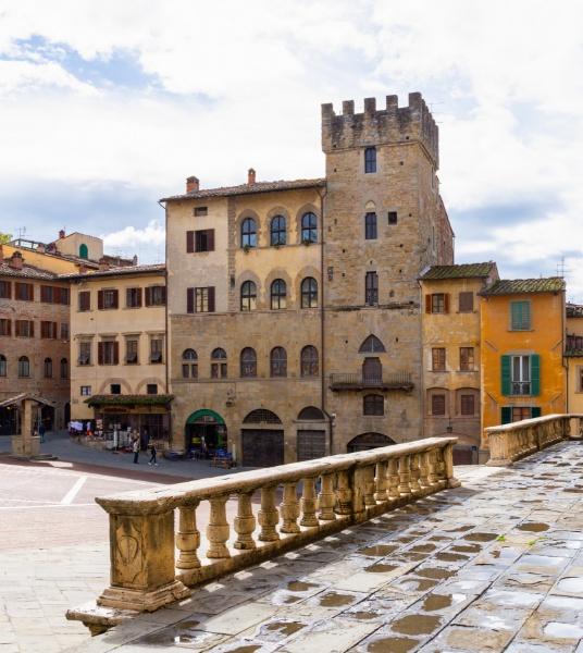 Square with historic buildings and a medieval stone tower.